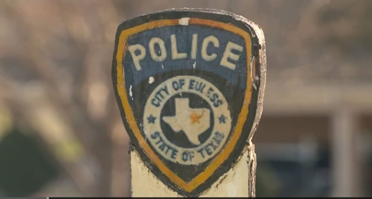 still from an interview video, it is a wooden post that has a police crest for the City of Euless